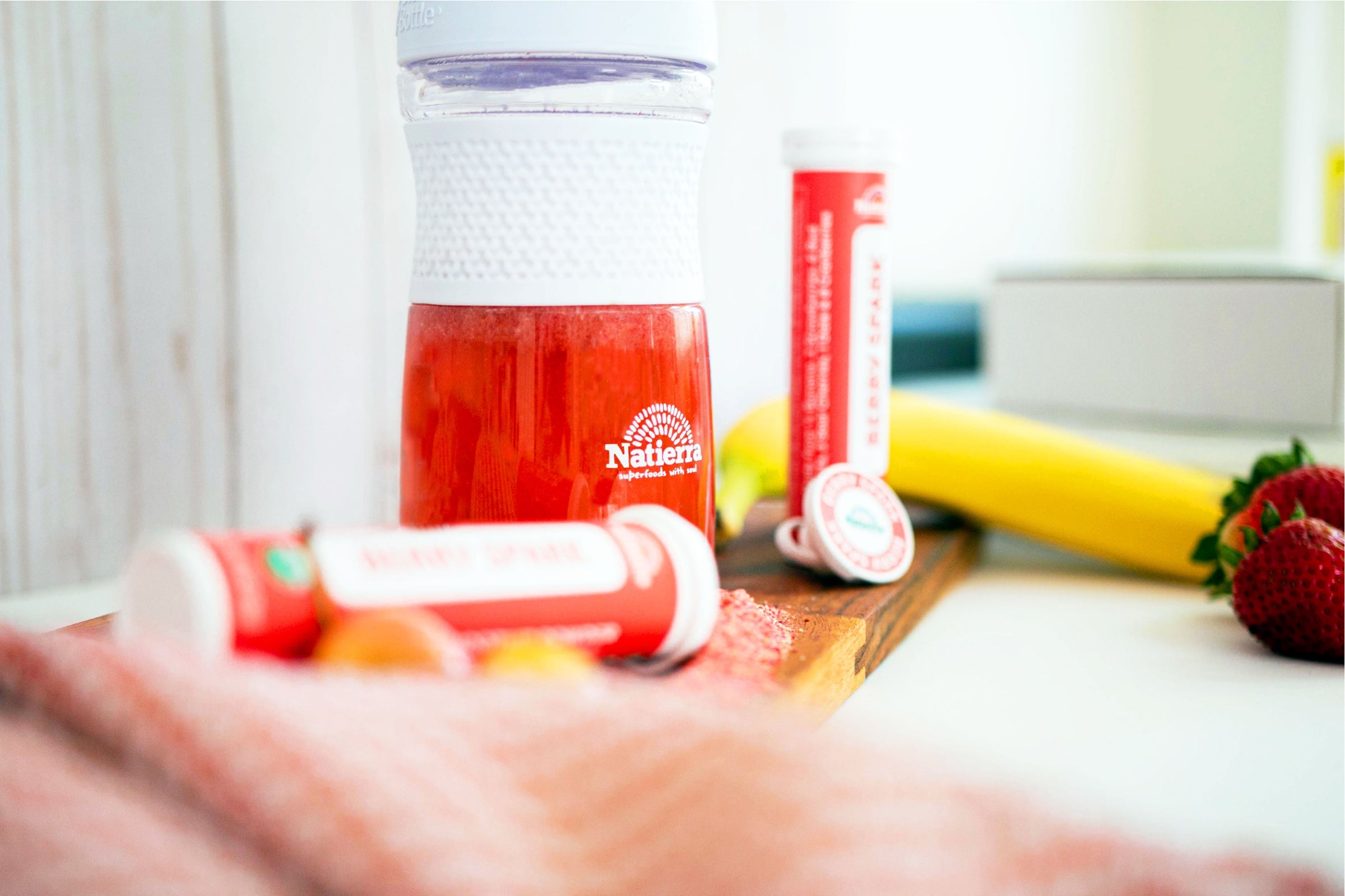 smoothie shaker and two Natierra smoothie tubes next to Banana and strawberry