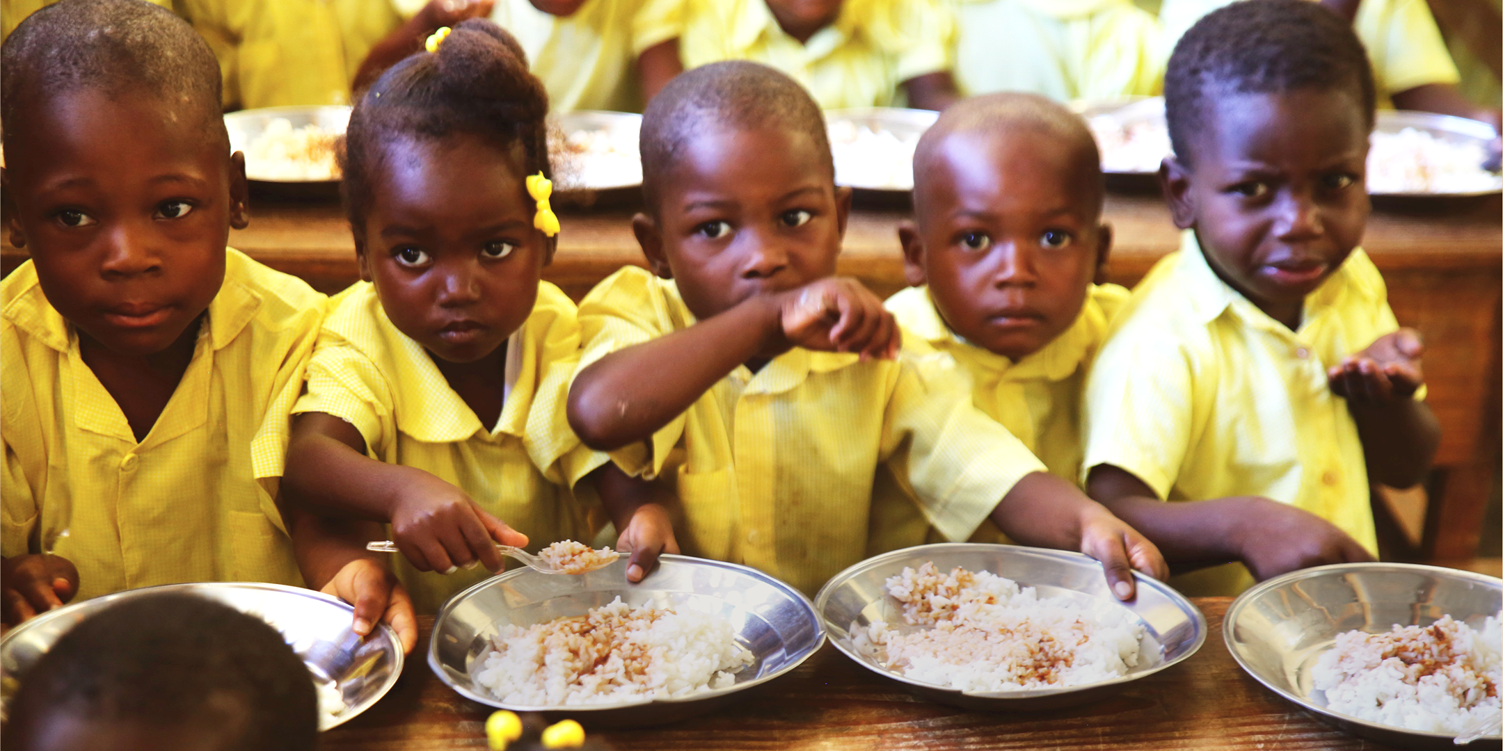 Children eating rice out of silver plates