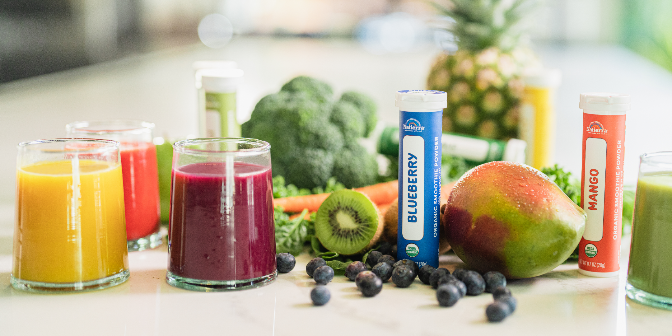 Natierra Organic Blueberry and Mango smoothie jars with smoothie in a glass