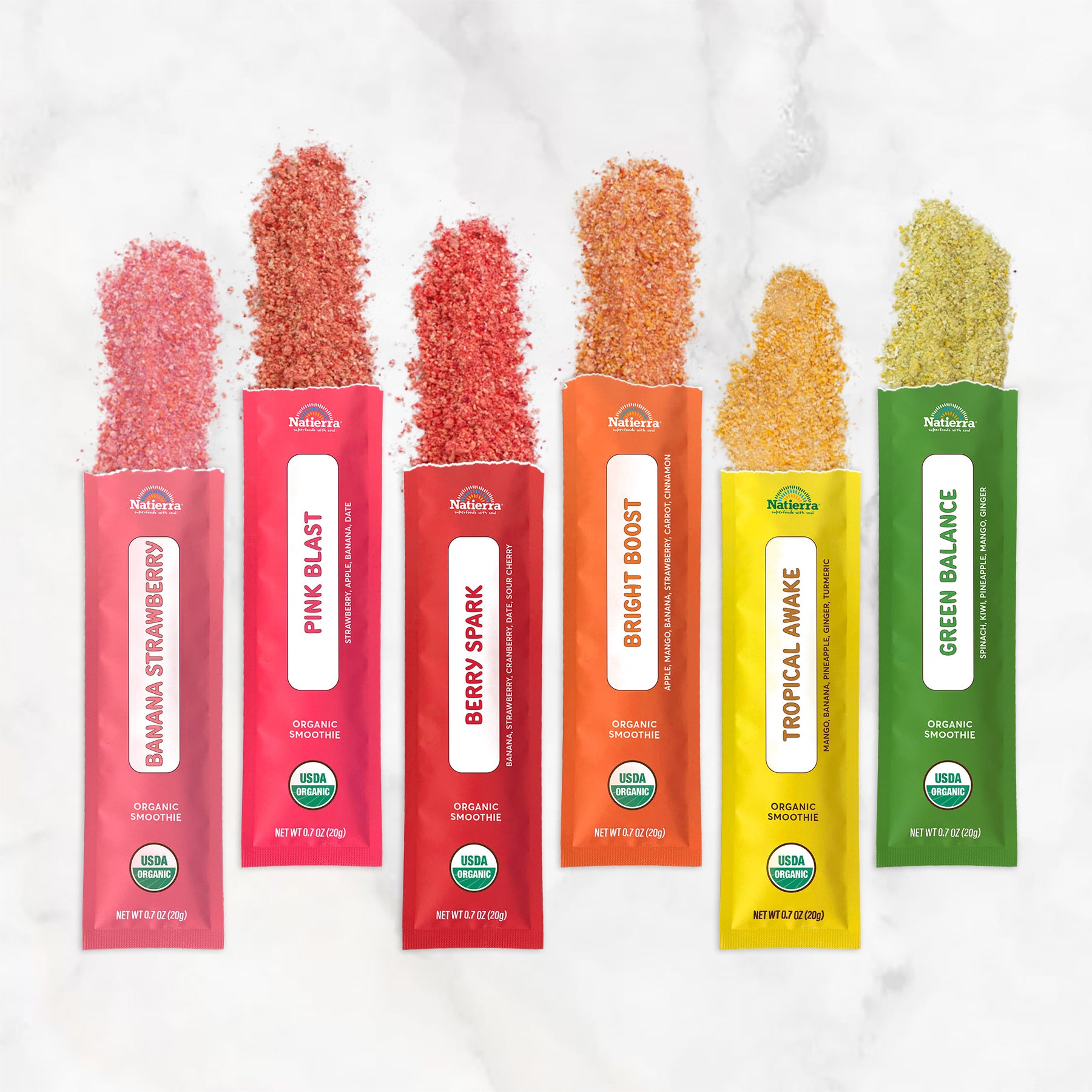 Shot of Natierra's Organic Smoothie individual stick packs on a marble counter top with colorful freeze-dried smoothie powder coming out of the packs