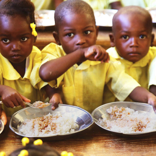 Children eating rice out of silver plates