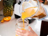 Blender pouring tropical awake organic smoothie in a jar