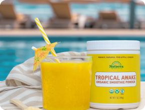 Photo of a jar and a glass of our Tropical Awake organic smoothie recipe in front of a pool