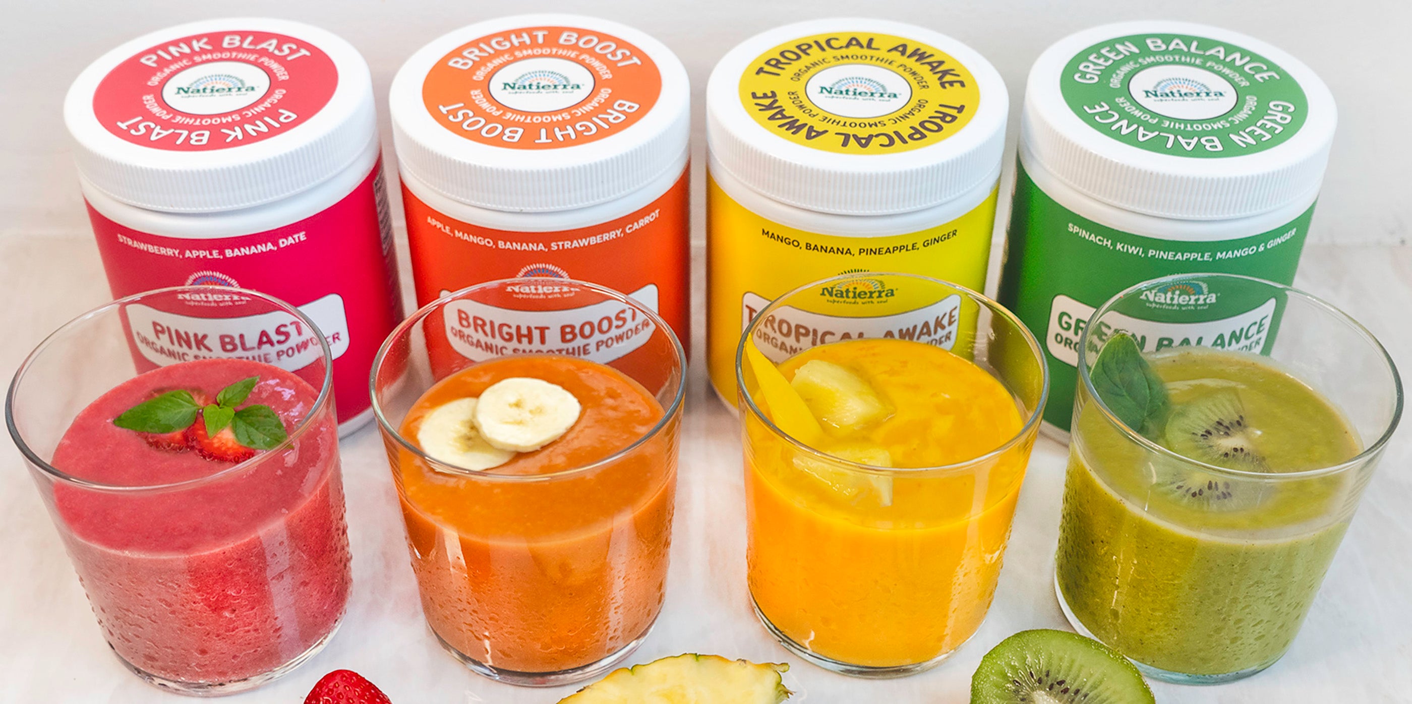 Four colorful smoothie drinks and Pink Blast, Bright Boost, Tropical Awake and Green Balance smoothie jar in background.
