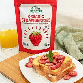 A plate of french toast topped with Natierra Organic Freeze-Dried Strawberries and a glass of orange juice 