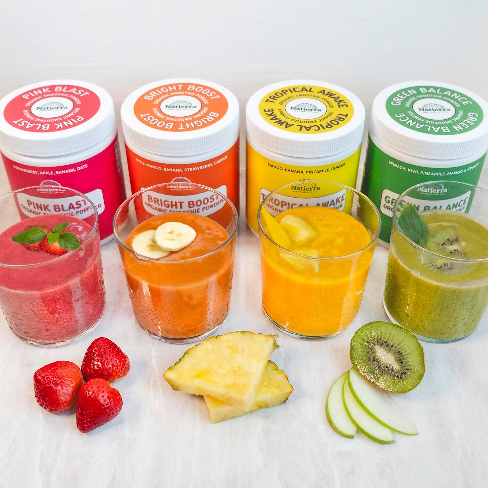 Four colorful smoothie drinks and Pink Blast, Bright Boost, Tropical Awake and Green Balance smoothie jar in background.