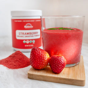 A glass of Nateirra's Organic Stawberry Smoothies  with the prodcut in the background