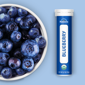 Natierra Organic Blueberry Smoothie Powder tube next to bowl of blueberries